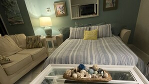 Ein Schlafzimmer mit einem Bett, einem Sofa, einem Glastisch und einer Lampe.