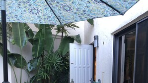 Ein Patio mit einem Esstisch, umgeben von Stühlen und einem dekorativen Sonnenschirm.