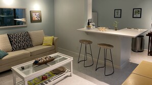 Ein modernes Wohnzimmer mit einer Couch, einem Couchtisch und einer Küchenzeile mit Barhocker.