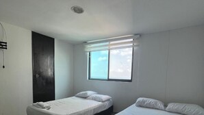 Une chambre avec deux lits, une fenêtre et une porte.