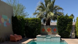 A rectangular swimming pool with a tiled edge, surrounded by a low wall and a palm tree. - Colorful Artist’s Mansion w. pool and spa, pet friendly, all utilities included (Palm Springs)