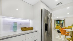 A modern kitchen with a stainless steel refrigerator, white cabinetry, a coffee machine, and a wicker basket on the countertop. - 5 BEDS / SLEEP 8 in a Prime Location in Miami! Near Airport/Cruise Terminal!  (Miami)