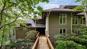 A two-story house with a wooden deck leading to the front door.