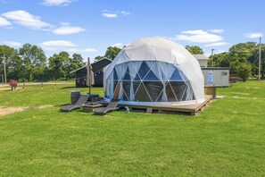 Una construcció amb forma de cúpula, una zona de pati coberta, una caseta petita i un barbacoa.