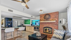 A modern living room with a fireplace, a kitchen area, and a bar. - Group Spa All Day. Connect All Night. Near WinStar. (Thackerville)