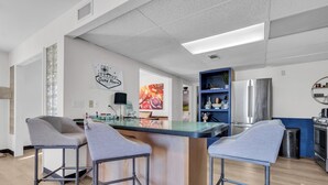 A modern kitchen with a central island, bar stools, a refrigerator, and a blue shelving unit. - Group Spa All Day. Connect All Night. Near WinStar. (Thackerville)