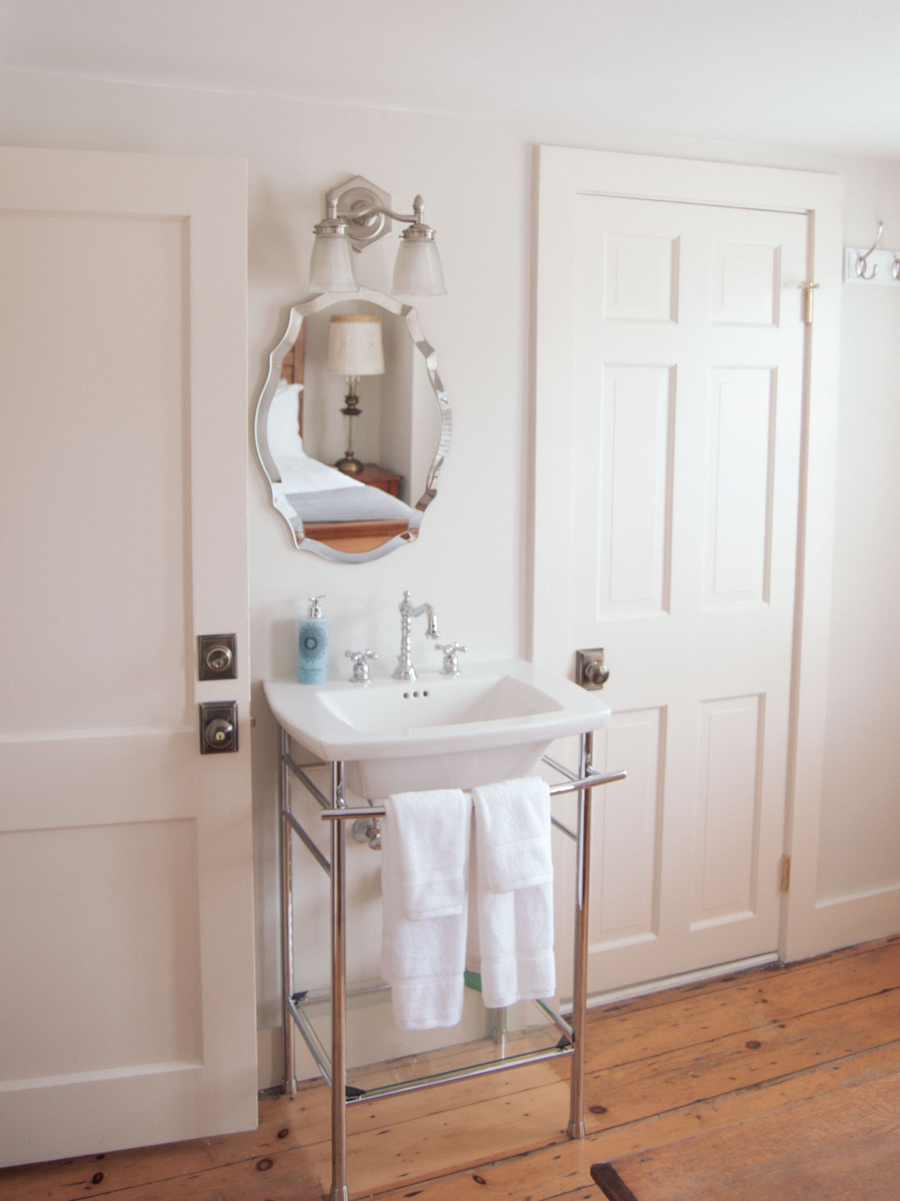A bathroom with a white sink, a mirror, and a towel rack.