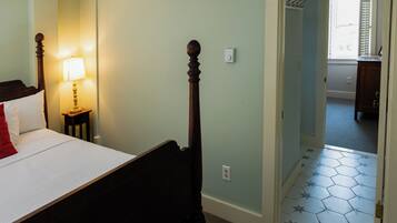 A bedroom with a bed, bedside lamp, and a door leading to another room.