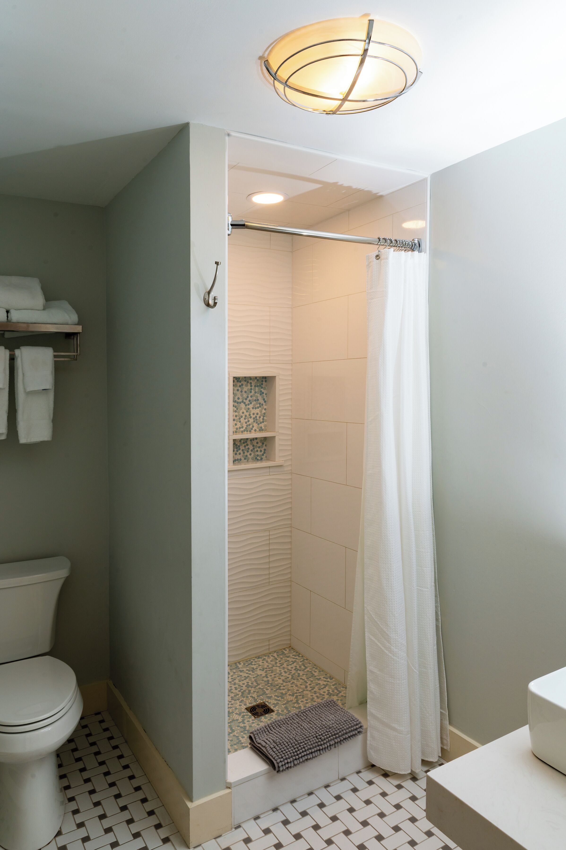 A bathroom with a shower, toilet, and a towel rack.