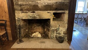 A stone fireplace with a rustic design, a wooden chair to the left, and a dining area visible through the doorway. - The General Stanton Inn (Charlestown)
