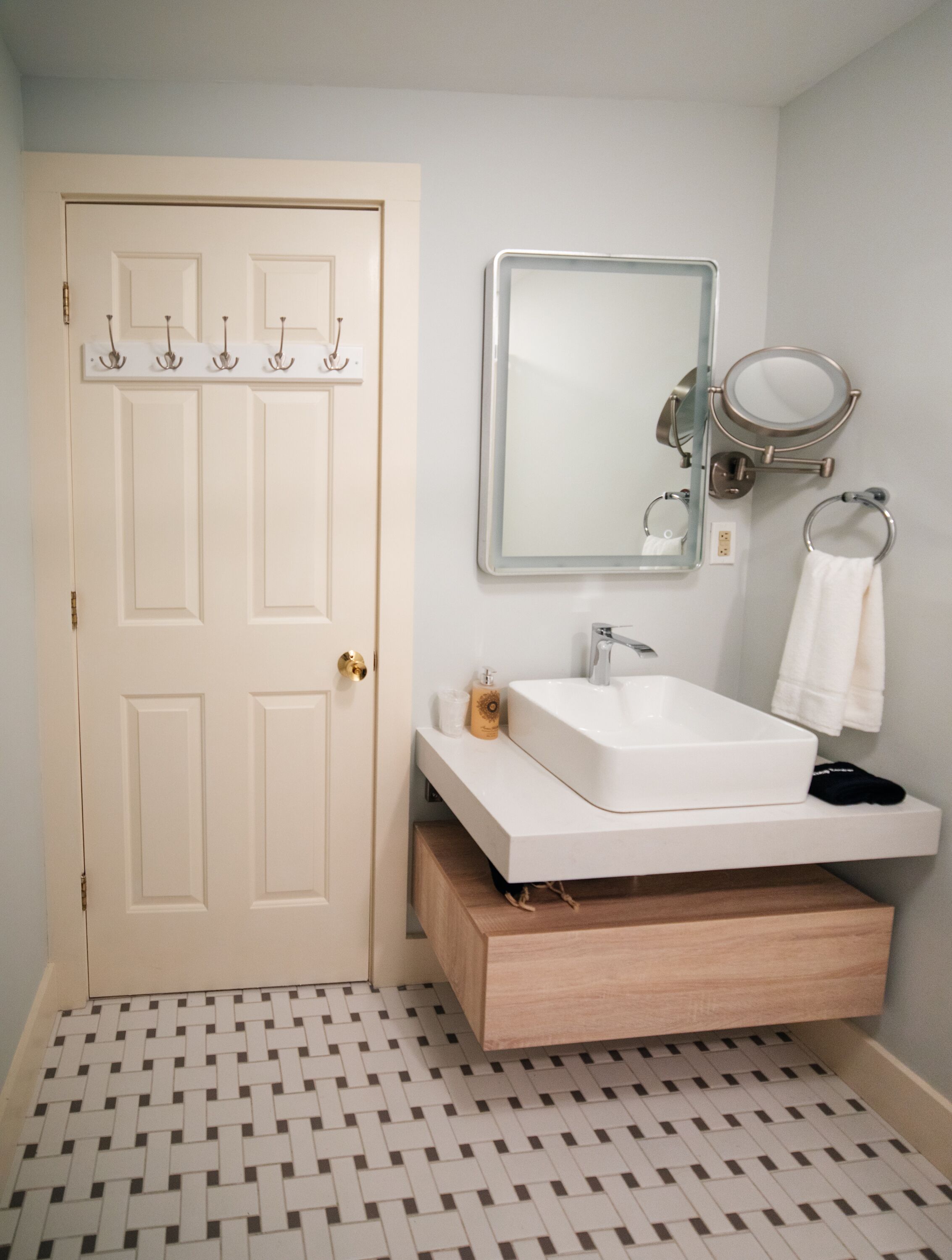 A bathroom with a white sink, a mirror, and a towel rack.