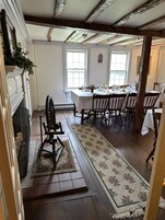 Comedor con mesa de madera dispuesta para cuatro personas, flanqueada por dos ventanas.