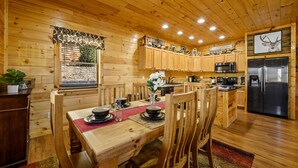 Ein Holzblockhaus-Interieur mit Essbereich, Küche und einem Fenster mit Blick.
