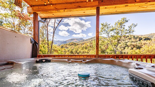 Ein Whirlpool mit einer Holzterrasse und Blick auf eine Berglandschaft.