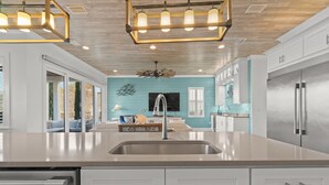 Une cuisine moderne dotée d’un grand îlot central, d’appareils électroménagers en acier inoxydable et d’un mur d’accent de couleur turquoise.