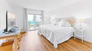 Habitació d'hotel moderna amb un llit gran, televisió, escriptori i un balcó amb vista al mar.