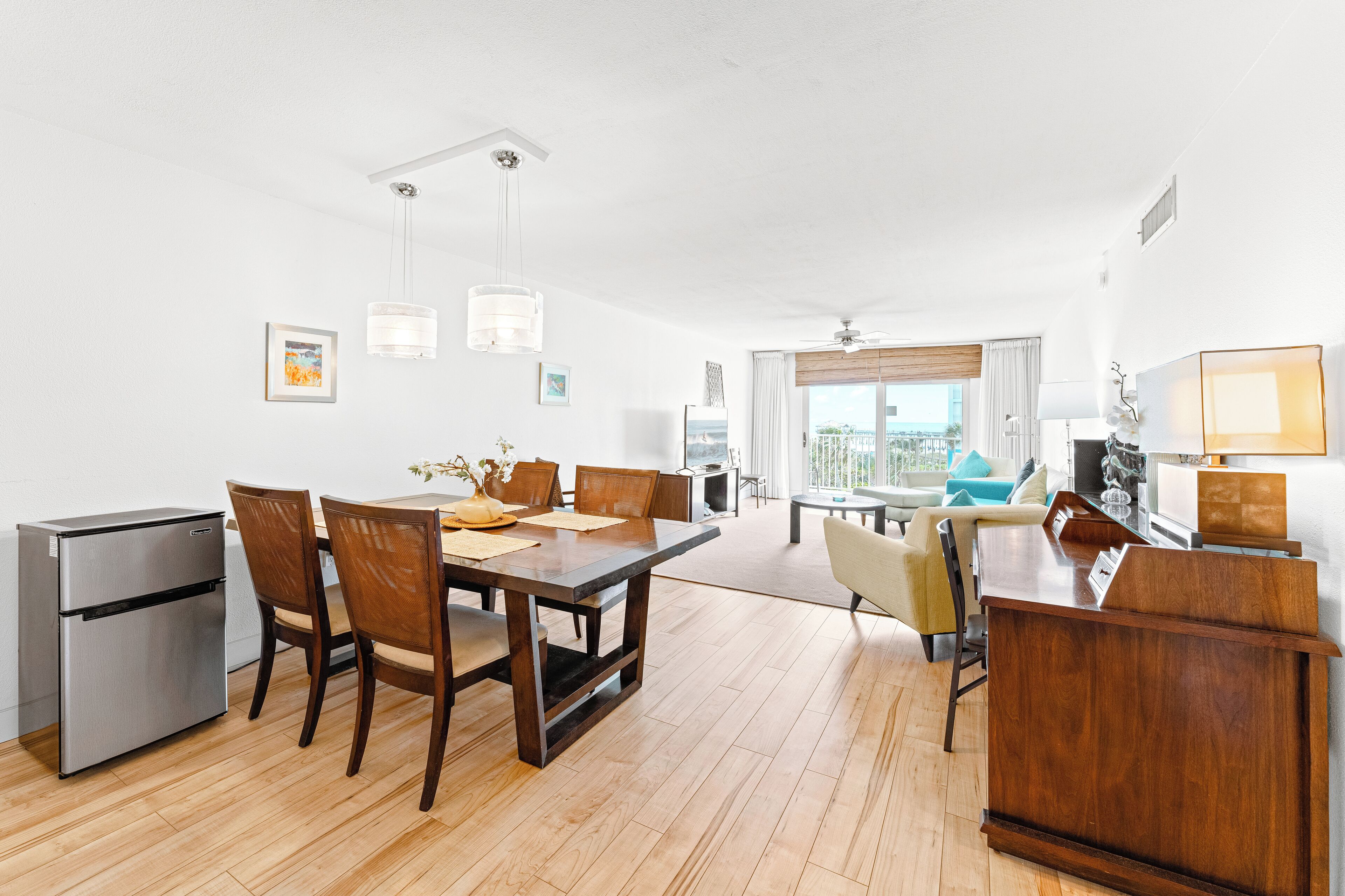A modern kitchen with a dining area, wooden flooring, and a view of the city.