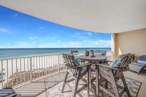 Un balcon avec vue sur la plage et l’océan, aménagé avec une table et des chaises, et agrémenté d’un tapis à motifs.