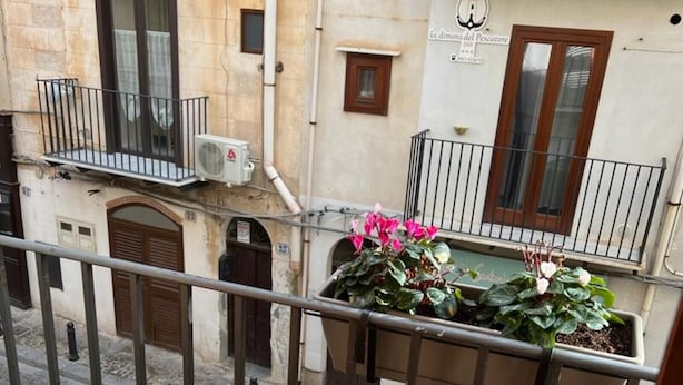 A wooden table with a lantern and a glass on a balcony with a metal railing.