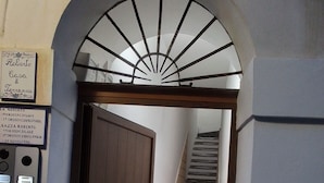 A staircase with a wooden door and a metal handrail, leading to an upper floor.