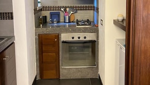 A compact kitchen with a built-in oven, a countertop with various appliances, and wooden cabinets.