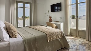 Ein Hotelzimmer mit Bett, Schreibtisch, Fernseher und großen Fenstern.
