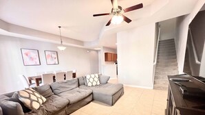 Un salon moderne avec un canapé d’angle, un ventilateur de plafond et un meuble pour la télévision.