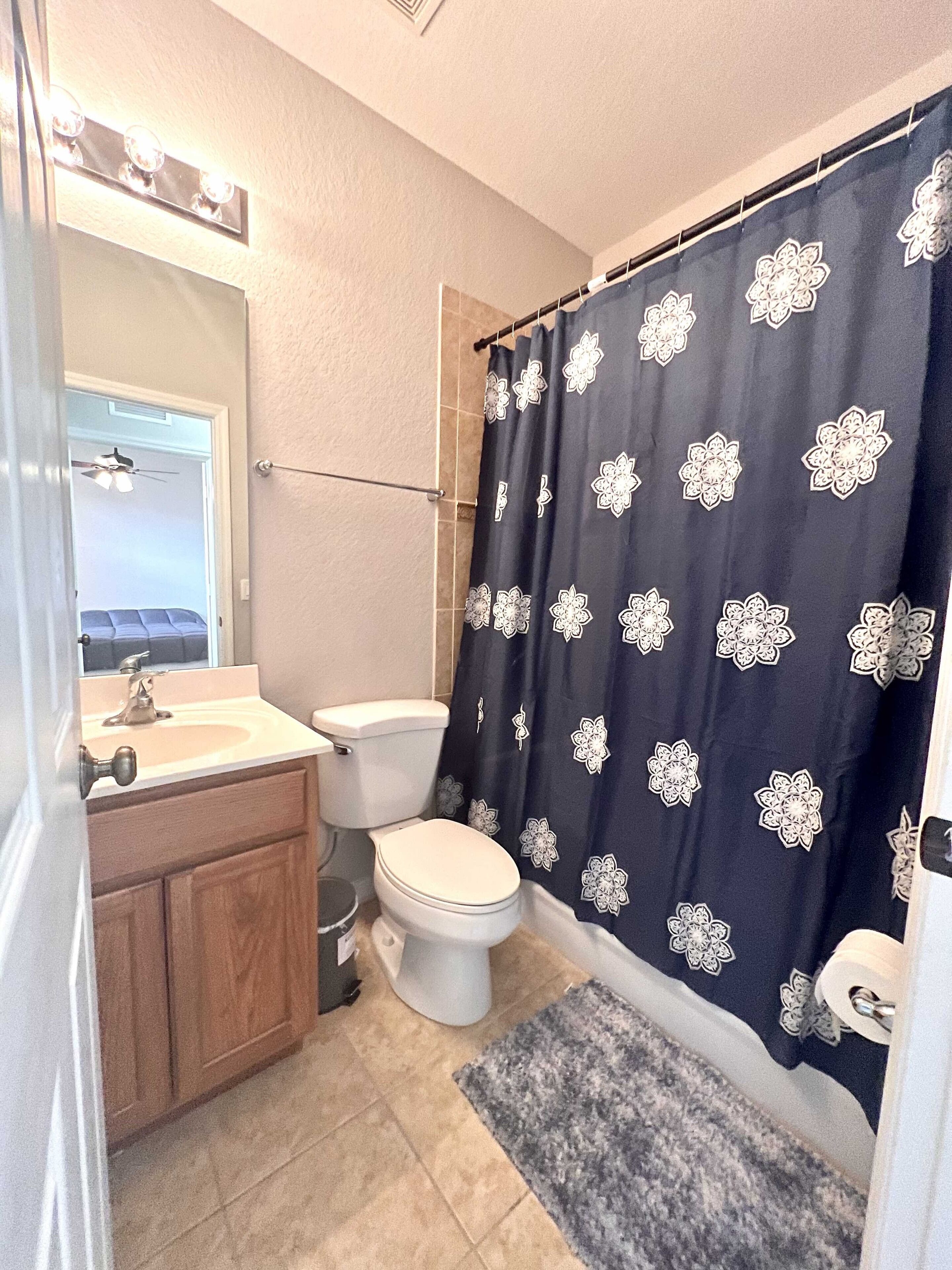 A bathroom with a toilet, sink, and mirror.