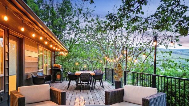 An outdoor deck with a fire pit, wicker furniture, and string lights. - Riverview Home - walking trails - convenient location (Clarkston)