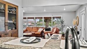 A modern kitchen with granite countertops, a built-in oven, and a dining area with a leather couch and dining table. - Riverview Home - walking trails - convenient location (Clarkston)