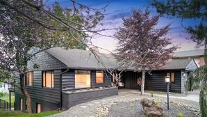 A modern house with a dark exterior, a gravel driveway, and a small garden area with rocks and plants. - Riverview Home - walking trails - convenient location (Clarkston)