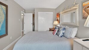 Een slaapkamer met een bed, een nachtkastje, een lamp, een kaart en een spiegel met decoraties van zeesterren.