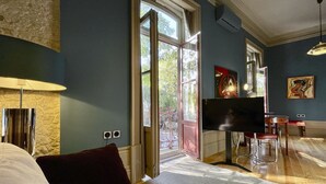 Een moderne hotelkamer met een groot bed, een televisie, een zithoek en uitzicht op het landschap.