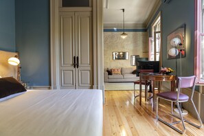 Une chambre d’hôtel avec un grand lit, un coin repas comprenant une table et des chaises, et un canapé à l’arrière-plan.