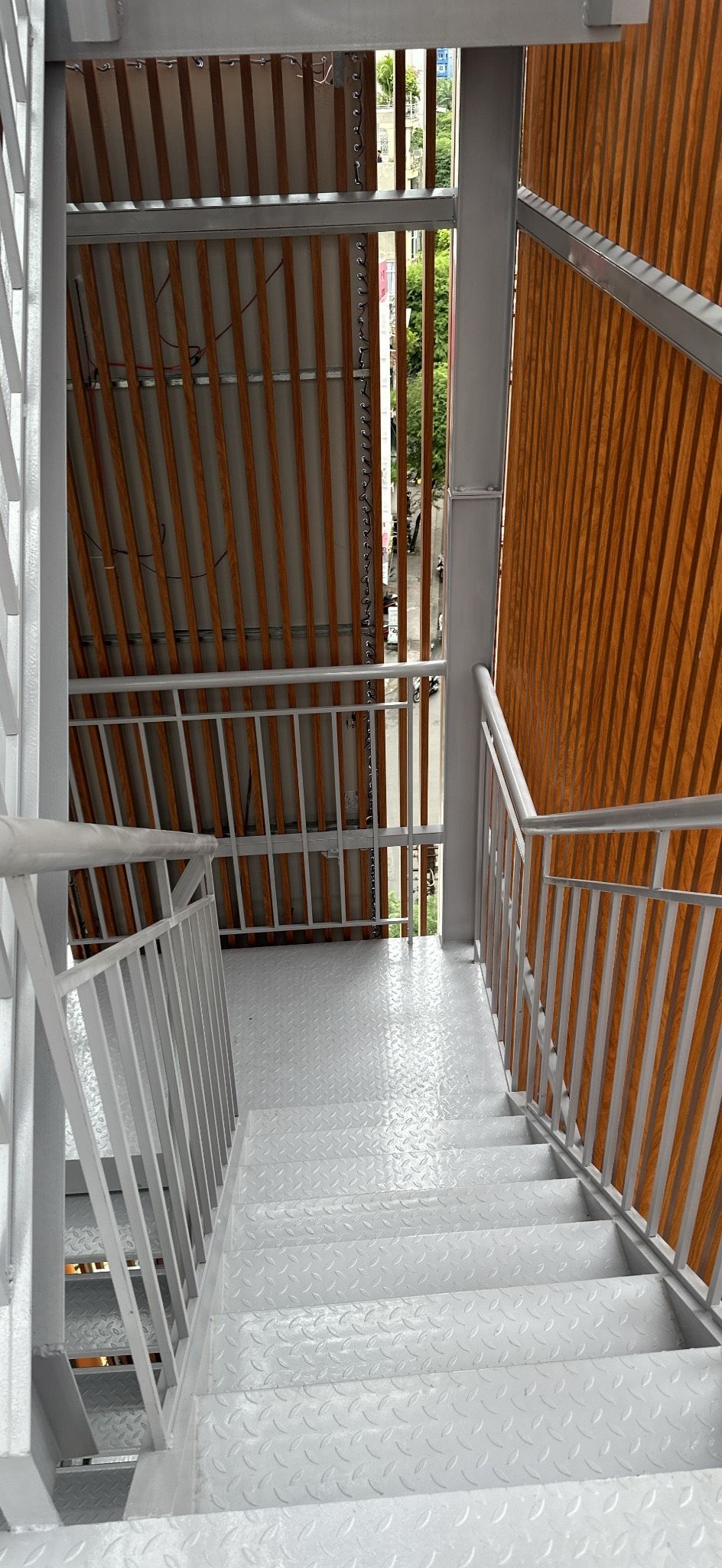 Una escalera con barandillas de metal y un panel de pared de madera.