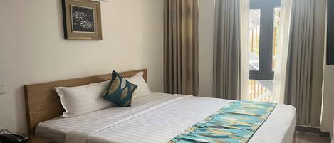 A neatly made bed with a blue and white patterned bedspread, a wooden headboard, and a single pillow with a leaf design.