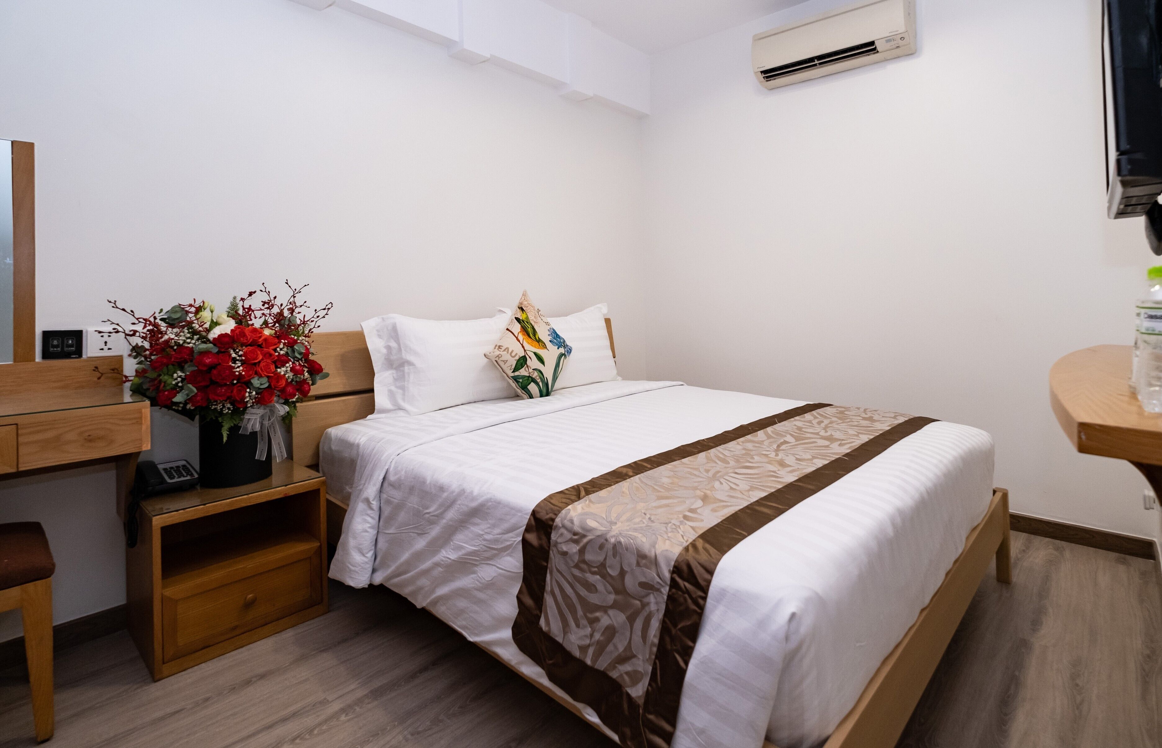 A neatly arranged bedroom with a bed, bedside table, and a desk with a chair.