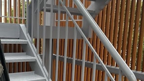 Una escalera metálica con escalones blancos y barandilla de metal.