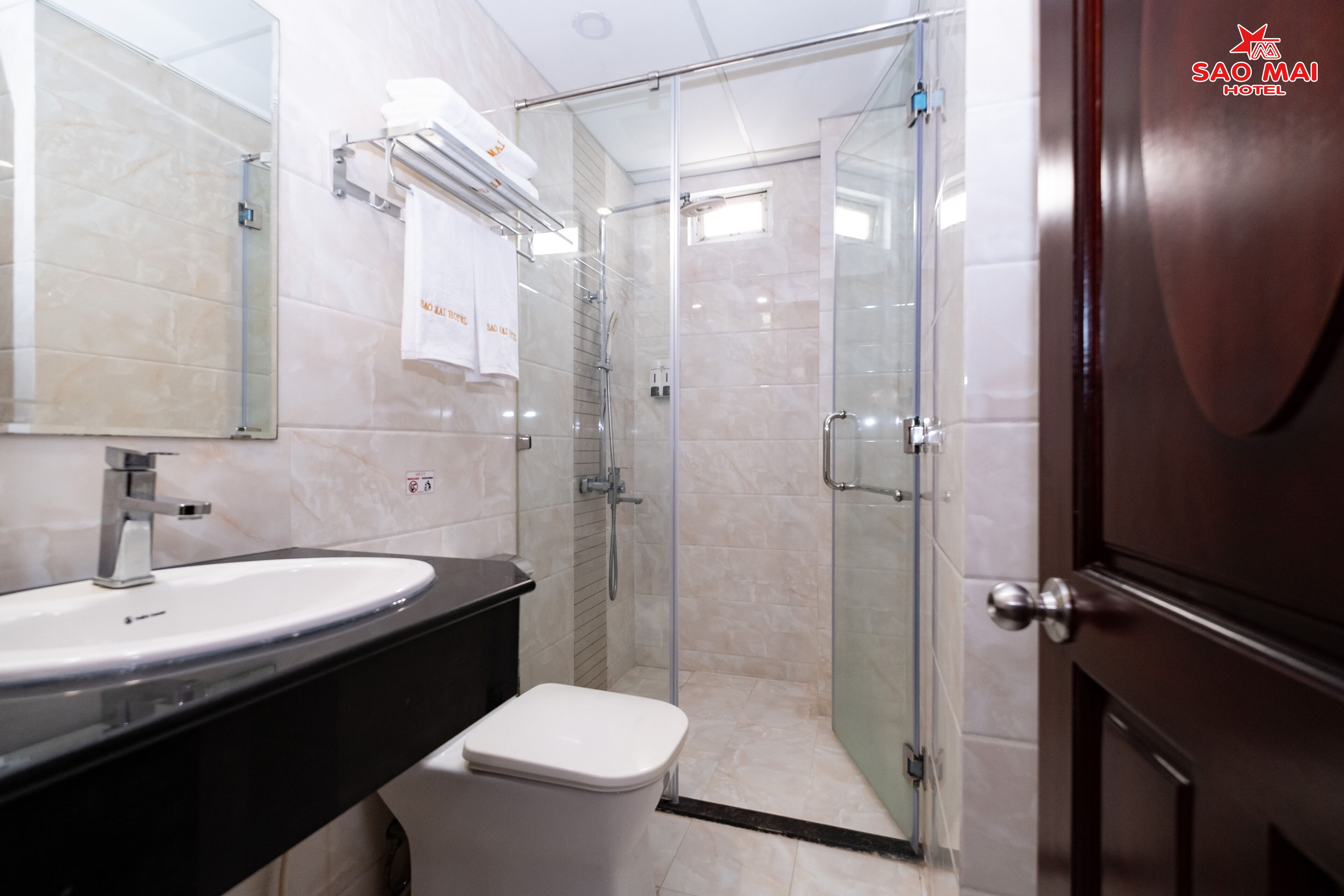 A modern bathroom with a large sink, mirror, and glass shower enclosure.