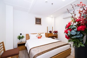 A modern hotel room with a neatly made bed, a bedside table with a lamp, a small plant, and a mirror on the wall. - Hotel Sao Mai (Ho Chi Minh City)