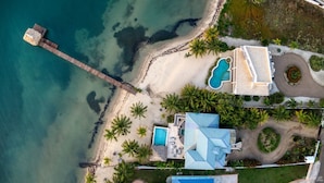 Ein Küsteneigentum mit Strand, Schwimmbad und einem großen Haus mit blauem Dach.