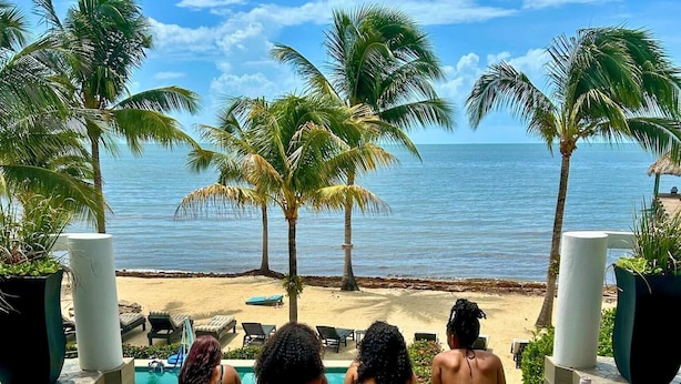Ein Pool mit klarem Wasser, umgeben von Palmen und Blick auf den Strand.