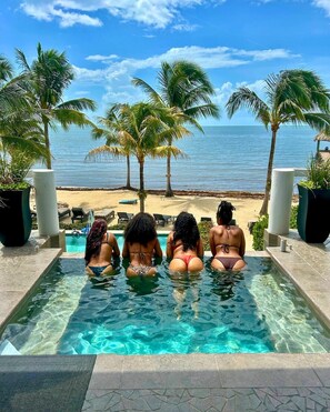 A pool with clear water, surrounded by palm trees and a view of the beach. - Luxury Oceanfront Villa w/ 2 Pools, Beach & Pier (Placencia)