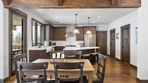 A modern kitchen with wooden cabinets, a central island, and pendant lighting. - The Sunrise Ridge Chalet (Whitefish)