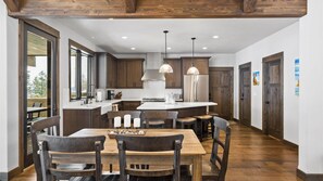 A modern kitchen with wooden cabinets, a central island, and pendant lighting.