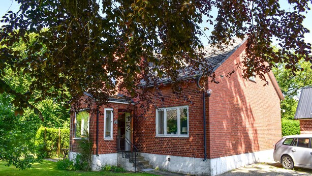A red brick house with a white trim, a front door, and a small porch.
