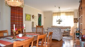 A dining area with a wooden table and chairs, a chandelier, and a patterned rug.