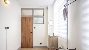A hallway with a wooden door, a small window, and a mirror on the wall.