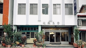 A building with a white facade, multiple windows with metal grilles, and a sign with Chinese characters.