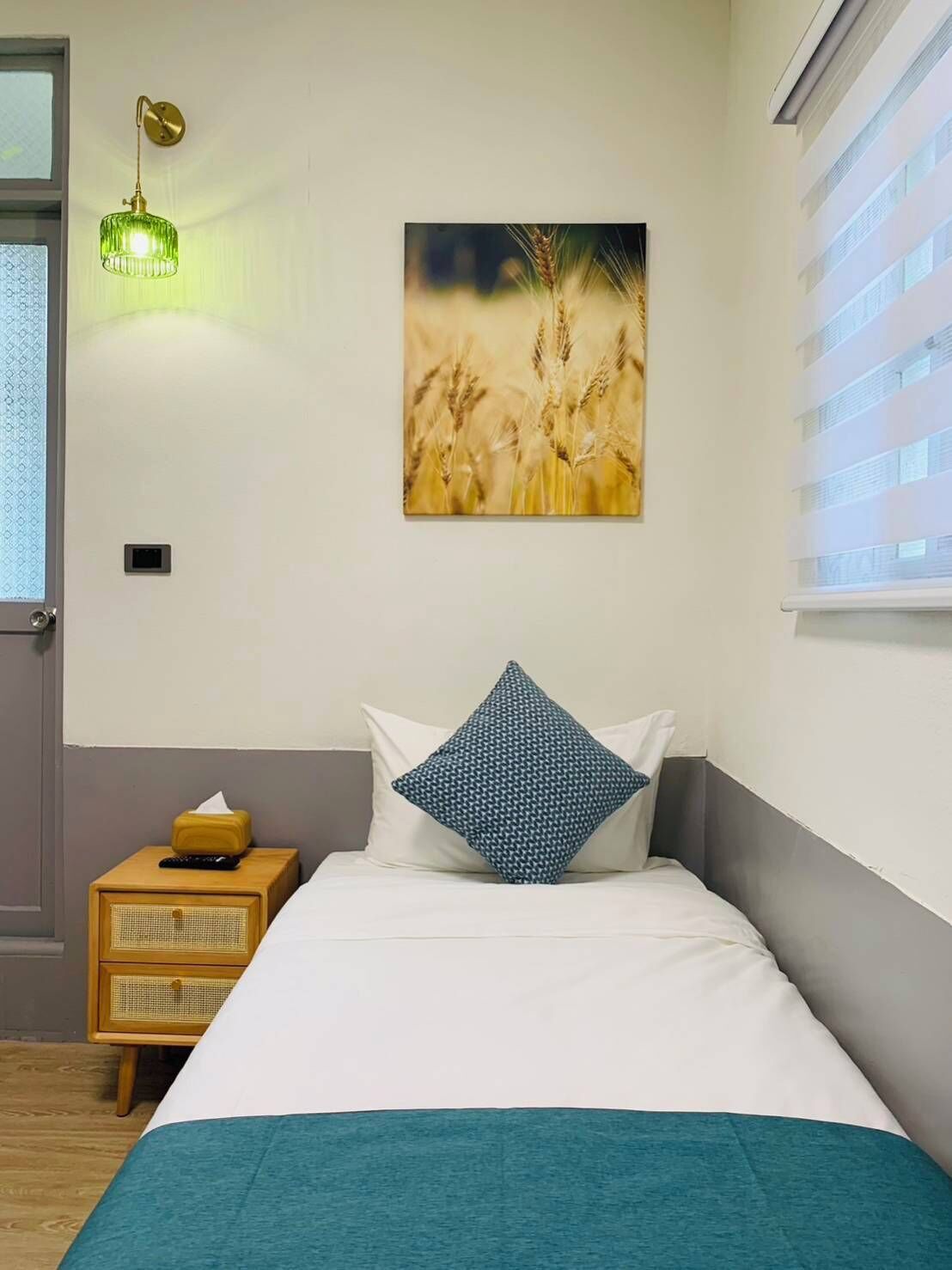 Une chambre à coucher avec un lit, une table de chevet, une lampe et un tableau accroché au mur.